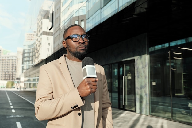 Journaliste africain tenant un microphone et parlant, il travaille dans la chaîne d'information