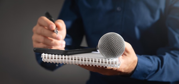 Journaliste caucasien tenant un bloc-notes et un stylo de microphone