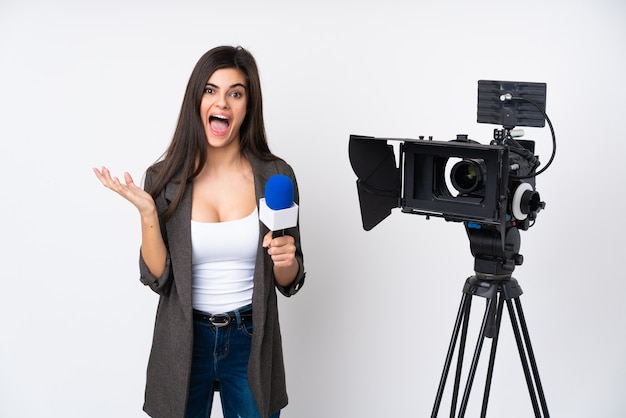 Journaliste femme tenant un microphone et rapportant des nouvelles sur le mur blanc mécontent et frustré par quelque chose
