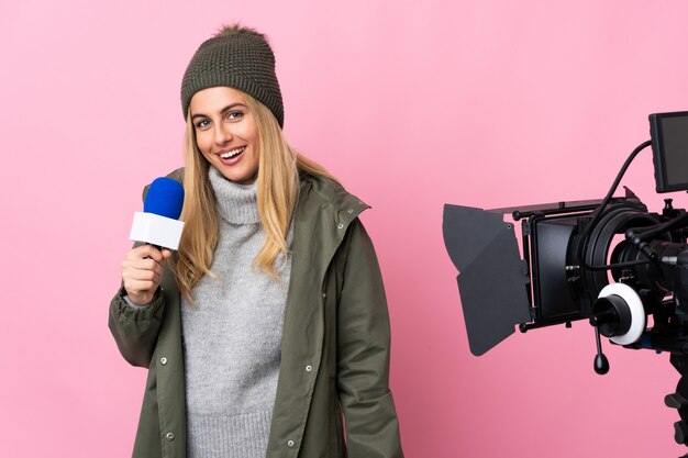 Journaliste femme tenant un microphone et rapportant des nouvelles sur rose isolé