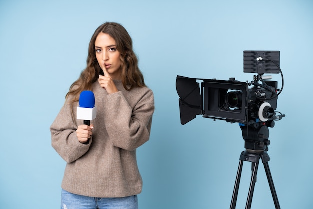 Journaliste jeune femme tenant un microphone et rapportant des nouvelles faisant un geste de silence