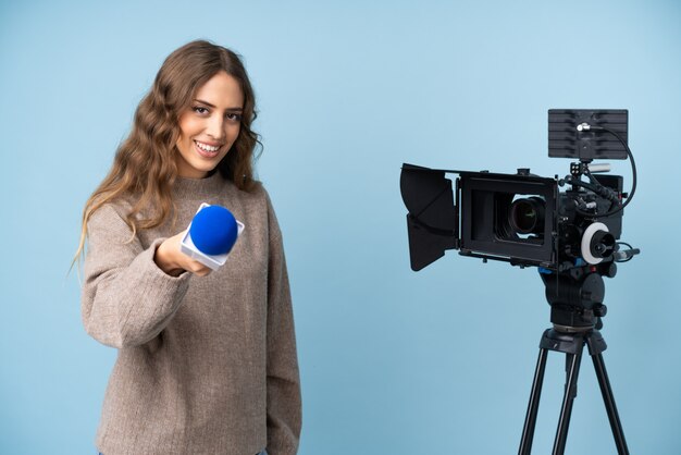 Journaliste jeune femme tenant un microphone et rapportant des nouvelles