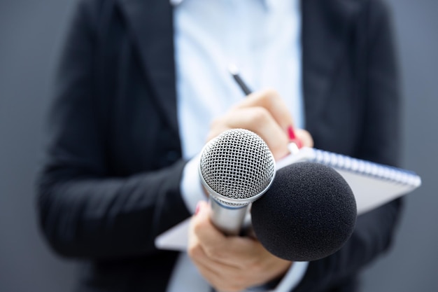 Journaliste lors d'une conférence de presse ou d'un événement médiatique écrivant des notes en tenant un microphone
