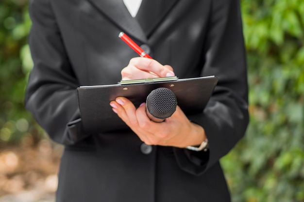 Journaliste portant des vêtements noirs tenant un microphone