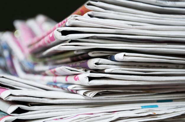 Journaux pliés et empilés sur le fond sombre de la table. Journal en gros plan et image de mise au point sélective.