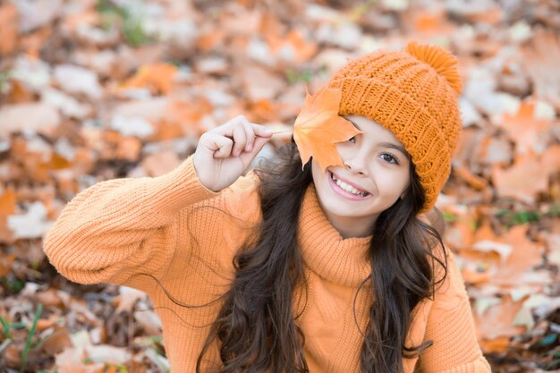 Journée d'automne parfaite d'une fille joyeuse en bonnet tricoté et pull se détendre dans la forêt de la saison d'automne en profitant du plaisir d'automne par beau temps