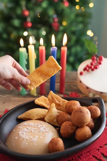 Journée aux chandelles. Cuisine colombienne typique. Buñuelo, crème pâtissière et flocons avec bougies et arbre de Noël en arrière-plan. Fête traditionnelle colombienne. Vidéo verticale.