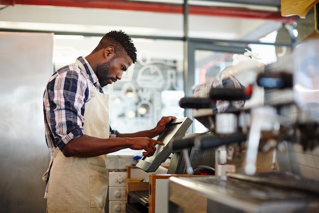 Journée bien remplie au café Photo recadrée d'un beau barista masculin travaillant dans un café