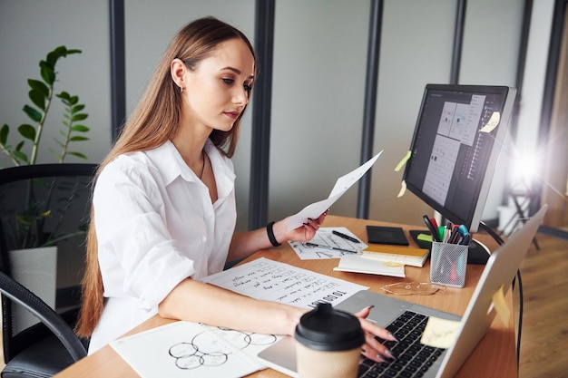 Journée bien remplie Jeune femme adulte en vêtements formels est à l'intérieur au bureau