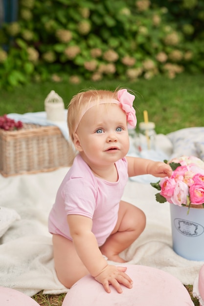 Photo journée des enfants, une fille dans le parc est assise dans un panier avec des macarons sur un pique-nique estival