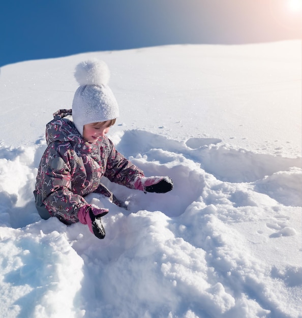 Journée ensoleillée d'hiver enfant jouant avec de la neige