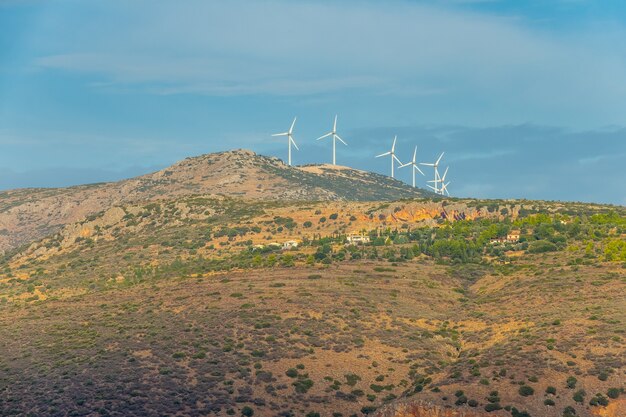 Journée d'été sur les collines en Grèce. Un petit village et plusieurs parcs éoliens au sommet d'une montagne