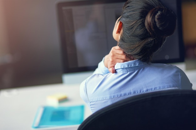 Cette journée a été une vraie douleur dans le cou Vue arrière d'une femme d'affaires souffrant de douleurs au cou au bureau