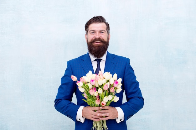 Journée de la femme. 8 mars. Cadeau de printemps. Homme barbu avec des fleurs. Célébrez le printemps. Monsieur avec des tulipes. Le printemps arrive. Un rendez-vous romantique. Laissez-moi vous inviter. Homme barbu avec bouquet de tulipes. Rendez-vous amoureux.