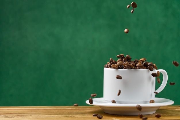 Journée internationale du concept de café. tasse de café blanc gros plan plein de grains de café. les grains de café tombent dans la tasse blanche