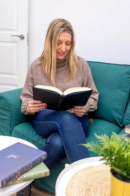 Journée internationale du livre Jeune femme assise sur un canapé souriant en lisant