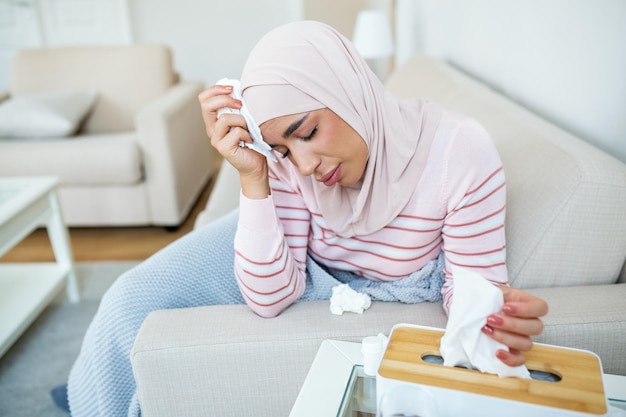 Journée de maladie à la maison Une jeune femme arabe a un rhume qui coule et une toux Gros plan d'une belle jeune femme avec le hijab attrapé une maladie du rhume ou de la grippe
