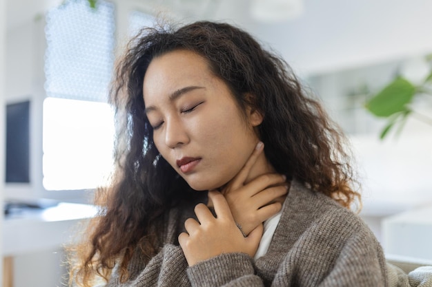 Journée de maladie à la maison Une jeune femme asiatique a mal à la gorge et au rhume Toux Gros plan d'une belle jeune femme attrapée par le rhume ou la grippe Portrait d'une fille malsaine avec des symptômes de coronavirus covid19