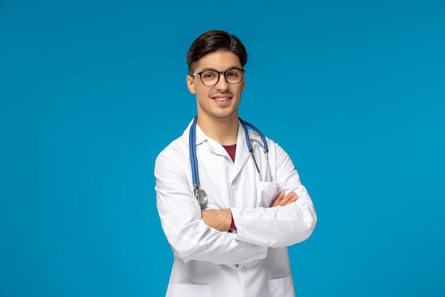 Journée des médecins beau mec mignon brune en blouse médicale avec les mains croisées