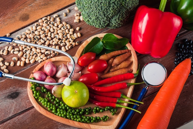 Journée mondiale de l'alimentation divers fruits et légumes biologiques frais dans une assiette cardiaque et un stéthoscope de médecin