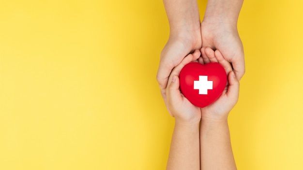 Journée mondiale de la croix rouge, mains adultes et enfants tenant coeur rouge