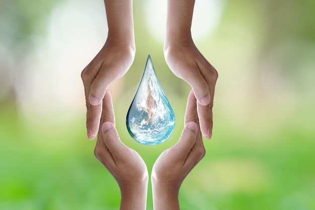 Journée mondiale de l'environnementmain humaine protégeant la goutte d'eau avec la lumière du soleil sur fond de nature verdoyante