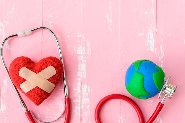 Journée mondiale de la santé, coeur rouge avec stéthoscope sur fond en bois rose.