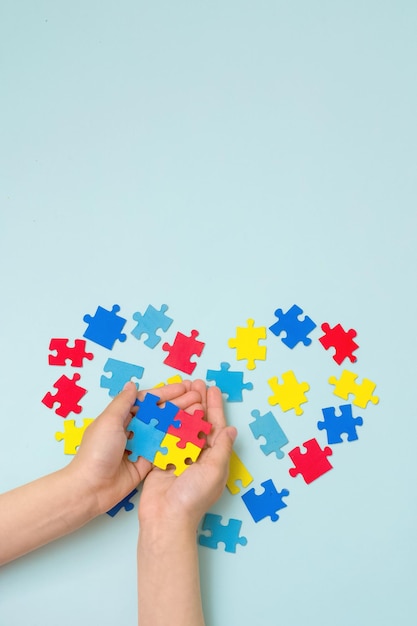 Journée mondiale de sensibilisation à l'autisme Journée de la fierté autistique Mains d'un petit enfant tenant des puzzles colorés