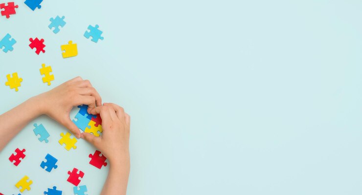 Journée mondiale de sensibilisation à l'autisme Journée de la fierté autistique Mains d'un petit enfant tenant des puzzles colorés