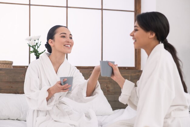 Journée romantique. Femmes joyeuses prenant le thé ensemble tout en passant une journée au spa