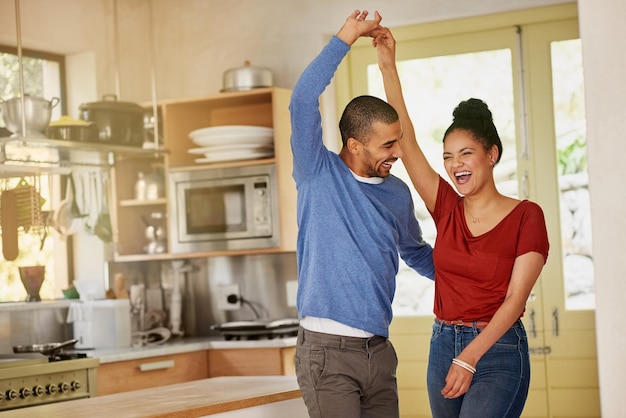 Des journées comme celles-ci étaient faites pour danser Photo d'un jeune couple heureux dansant ensemble à la maison