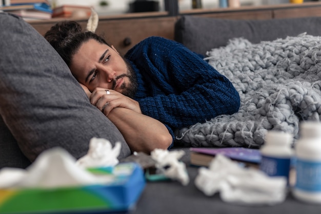 Jours difficiles. Triste homme triste allongé sur le canapé en pensant à sa maladie