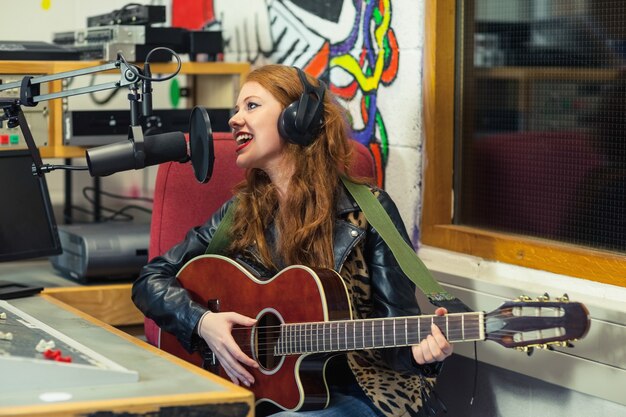 Joyeuse belle chanteuse d&#39;enregistrement et de jouer de la guitare