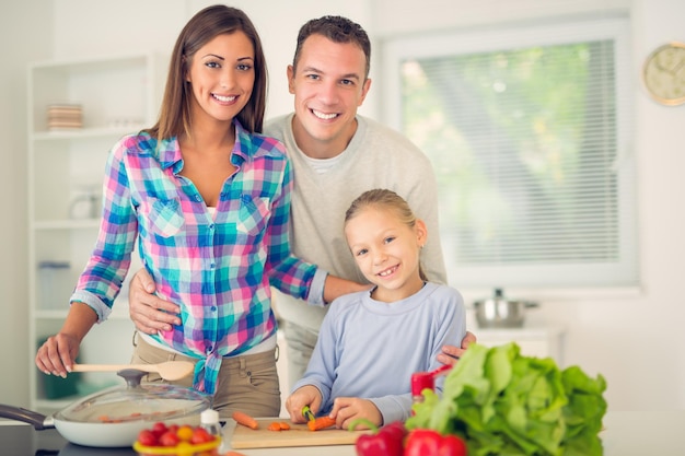 Joyeuse belle famille appréciant tout en préparant la nourriture dans la cuisine. Regarder la caméra.