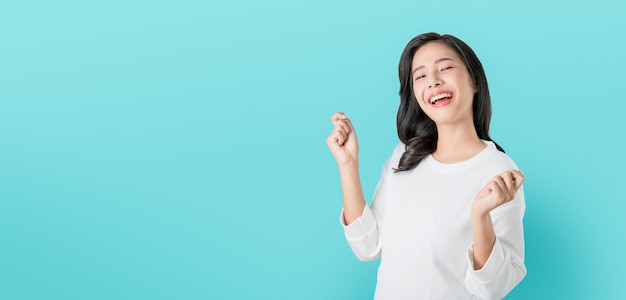 Joyeuse belle femme asiatique en t-shirt blanc décontracté et visage heureux sourire sur fond bleu