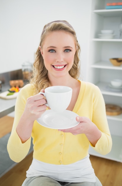 Joyeuse blonde mignonne tenant une tasse