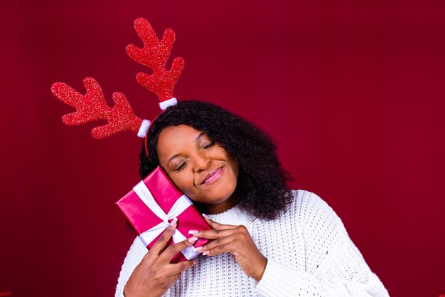 Joyeuse Brésilienne charmante femme en cornes de cerf jouet tenant une boîte-cadeau boule rouge