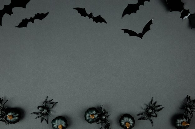 Joyeuse composition à plat d'halloween avec des citrouilles noires, des araignées et des chauves-souris sur fond sombre. Notion de vacances. Vue de dessus. Espace de copie.
