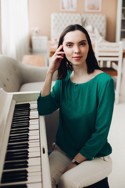 Joyeuse dame est assise sur la chaise près du piano blanc