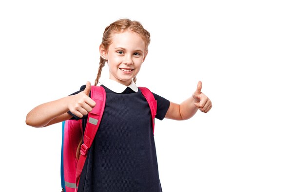 Joyeuse écolière de 8 ans avec sac à dos en uniforme debout isolé sur fond blanc. Prêt pour l'école.