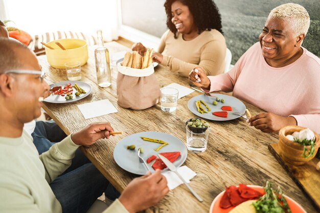 Photo joyeuse famille africaine déjeunant ensemble à la maison concentration douce sur la main droite de la mère