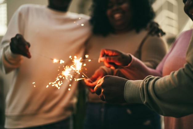 Joyeuse famille africaine utilisant des cierges magiques en plein air à la maison - Concentrez-vous sur la main droite