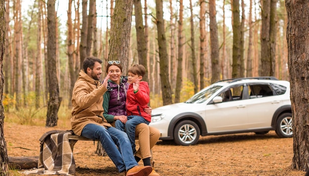 Joyeuse famille amicale jouant et s'amusant dans la forêt d'automne