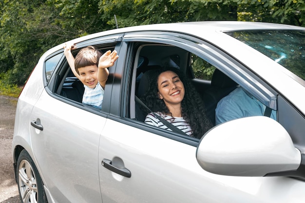 Joyeuse famille arabe millénaire joyeuse avec un garçon partant en vacances en voiture à l'été, un enfant agite sa main par la fenêtre