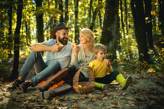 Joyeuse famille assise sur l'herbe lors d'un pique-nique dans un parc jeune famille souriante faisant un pique-nique o...