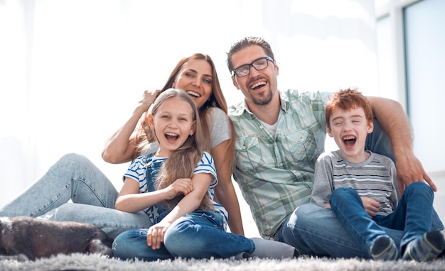 Joyeuse famille assise sur le tapis dans le nouveau salon