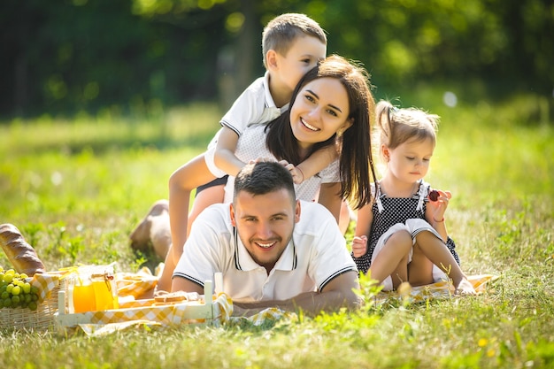 Joyeuse famille ayant pique-nique. Les parents en train de dîner avec leurs enfants à l'extérieur.