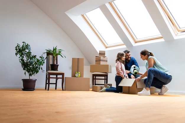 Joyeuse famille caucasienne emménageant dans une nouvelle maison et déballant des boîtes ensemble.