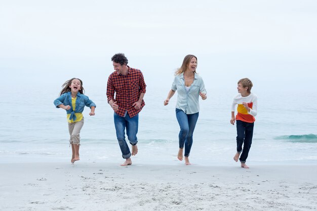 Joyeuse famille en cours d'exécution au bord de la mer contre le ciel