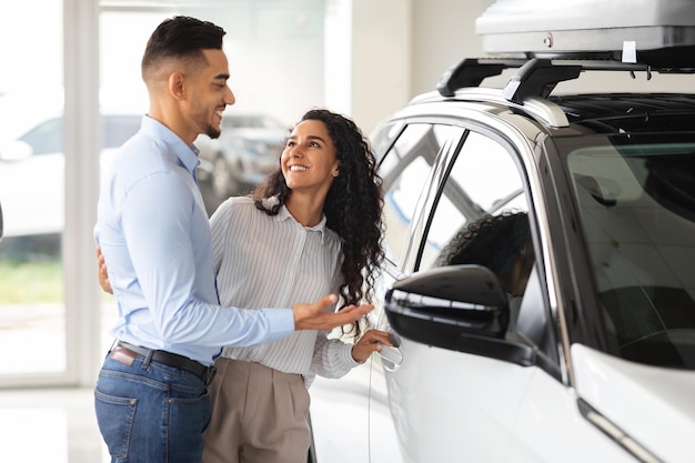 Joyeuse famille du Moyen-Orient choisissant une nouvelle voiture, debout près d'un véhicule blanc